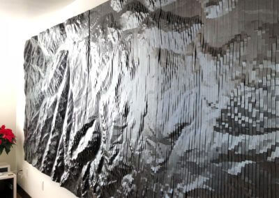 A large black stylized topographic map made from digitally fabricated linear sections
